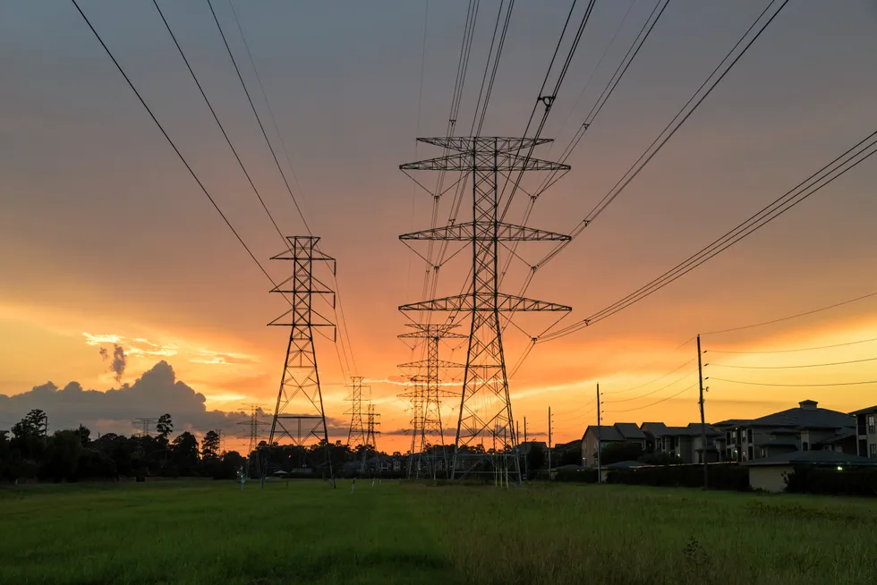 Group silhouette of transmission towers (power tower, electricity pylon, steel lattice tower) at sunset in Humble, Texas, US.