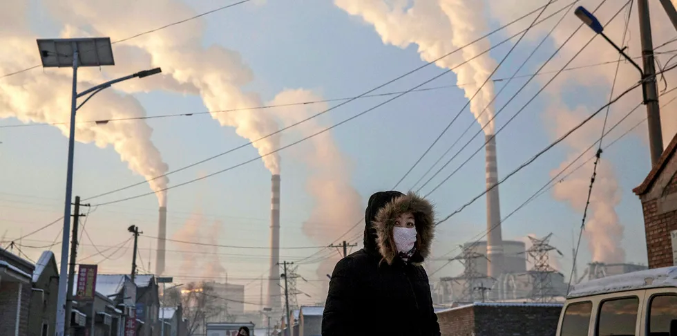 Smoke billows from stacks as a Chinese woman wears as mask while walking in a neighborhood next to a coal fired power plant on November 26, 2015 in Shanxi, China.