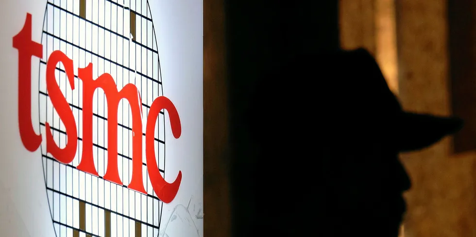 A security staff stands next to a logo of the Taiwan Semiconductor Manufacturing Co, (TSMC), during the investors conference in Taipei.