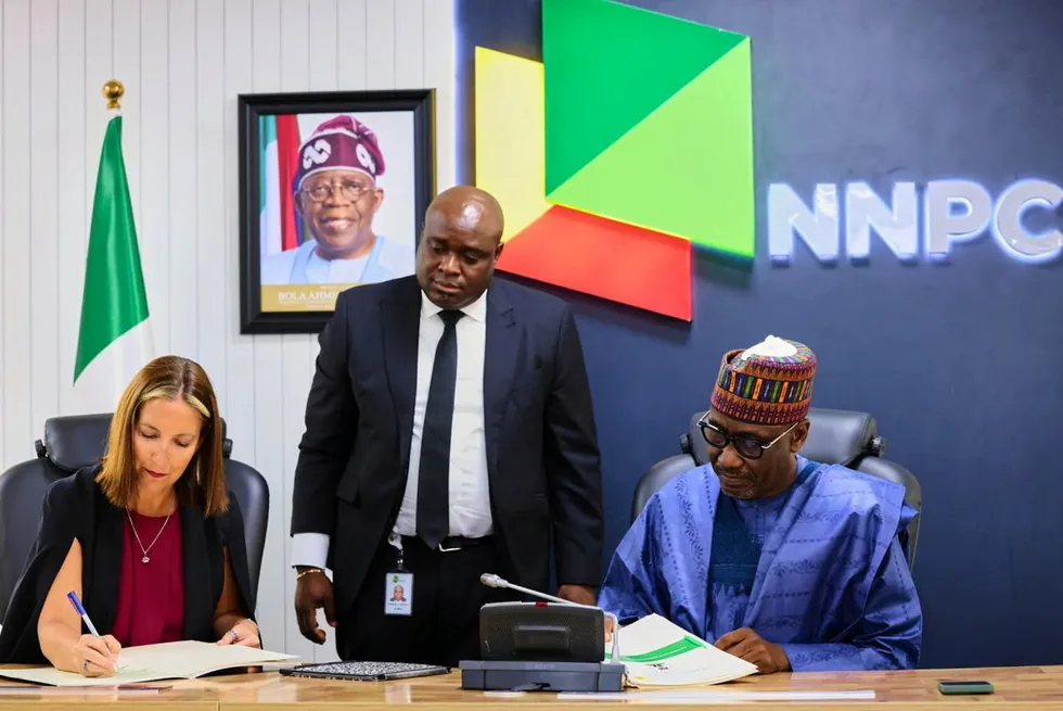 Michelle Pflueger, Chevron's deepwater director for Nigeria & Mid-Africa (left) and Mele Kyari, NNPC chief executive (right), sign licence conversion documents in Abuja, while Tolulope Ibikunle, NNPC's upstream business advisor, looks on.