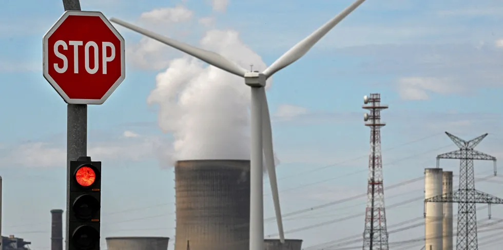 A wind turbine in front of a coal-fired power plant in Germany, which has reactivated mothballed plants to take the burden off gas.