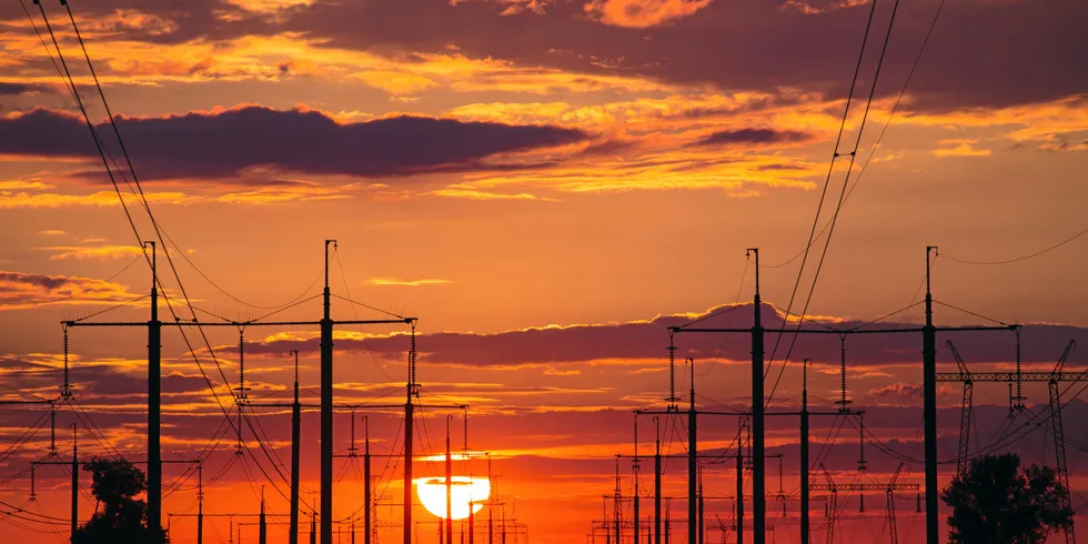 Sunset above high voltage power lines and electricity pylons on the fie