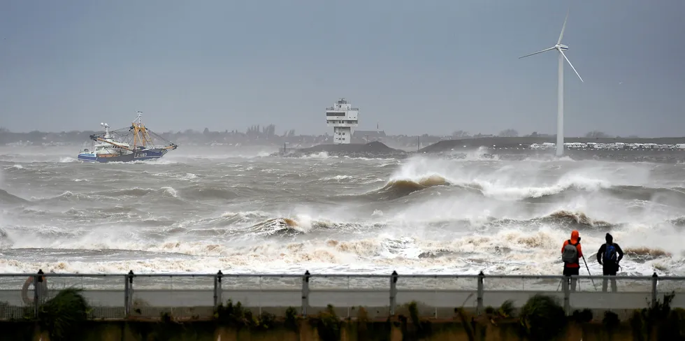 People watch as a fishing boat navigates stormy seas on its way into the River Mersey, in New Brighton, north west England, on February 9, 2020, as Storm Ciara swept over the country.