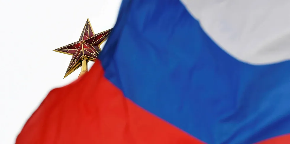 A Russian flag flies in front of a ruby star atop one of the Kremlin's towers