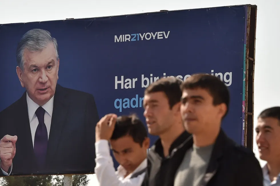 Strong lead: men walk past a campaign billboard of Uzbekistan's president and presidential candidate Shavkat Mirziyoyev in the town of Termez near the border with Afghanistan, about 800 kilometres from the Uzbek capital Tashkent