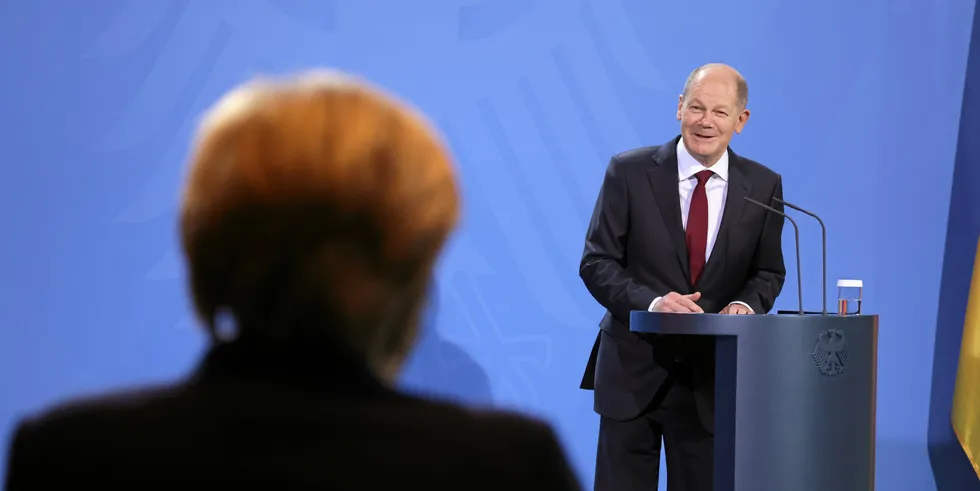 New Chancellor Olaf Scholz speaks during an official transfer of government, with Angela Merkel looking on.