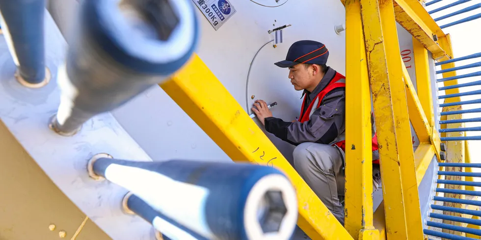 A staff member uses intelligent inspection technology to check the quality of fan blades on the inspection line of Shanghai Electric's wind turbine blade production line in Gansu province, China.