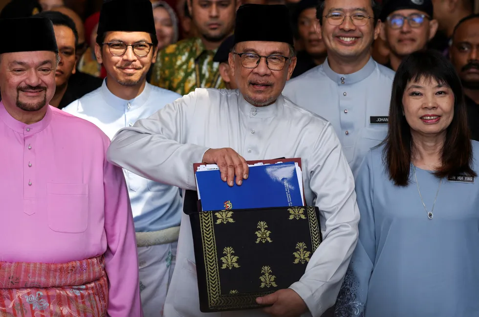 Malaysian Prime Minister, Anwar Ibrahim (centre), holds the 2025 Malaysia budget document at Parliament on 18 October.
