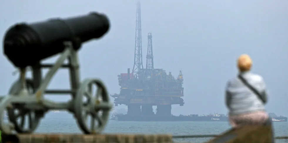 Fading fortunes: A member of the public stands on the shoreline looking out to sea, as Shell's Brent Delta Topside offshore oil drilling rig platform is towed by tug boats off the coast of Hartlepool, north-east England.