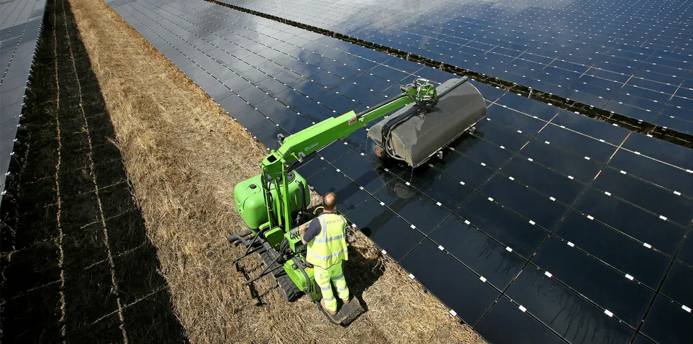 A workman uses a machine to clean panels at the 46MW Landmead solar farm near Abingdon, England