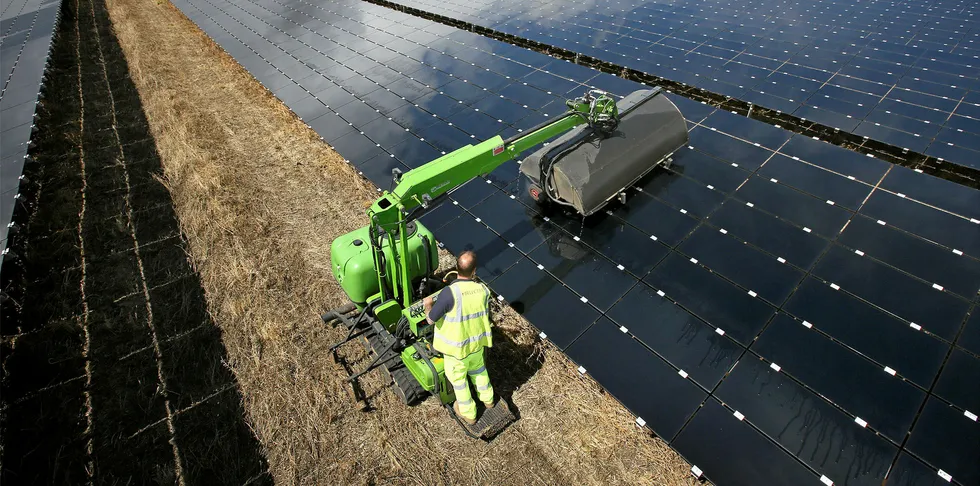 A workman uses a machine to clean panels at Landmead solar farm near Abingdon, England.