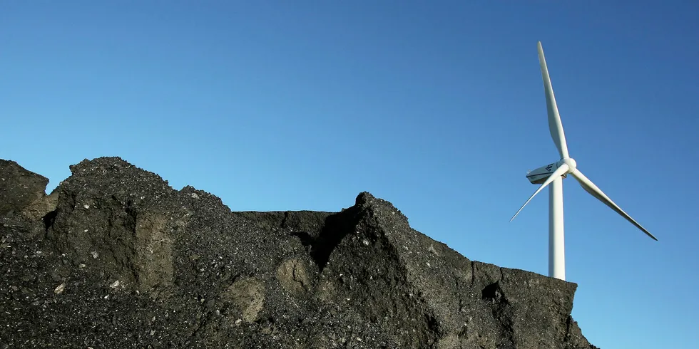 A wind turbine rises behind a mound of coal in Buettel, Germany.