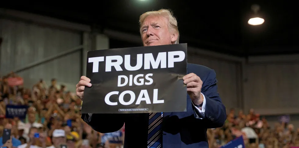 US President Donald Trump holds up a "Trump Digs Coal" sign as he arrives to speak during a Make America Great Again Rally in West Virginia in 2017.