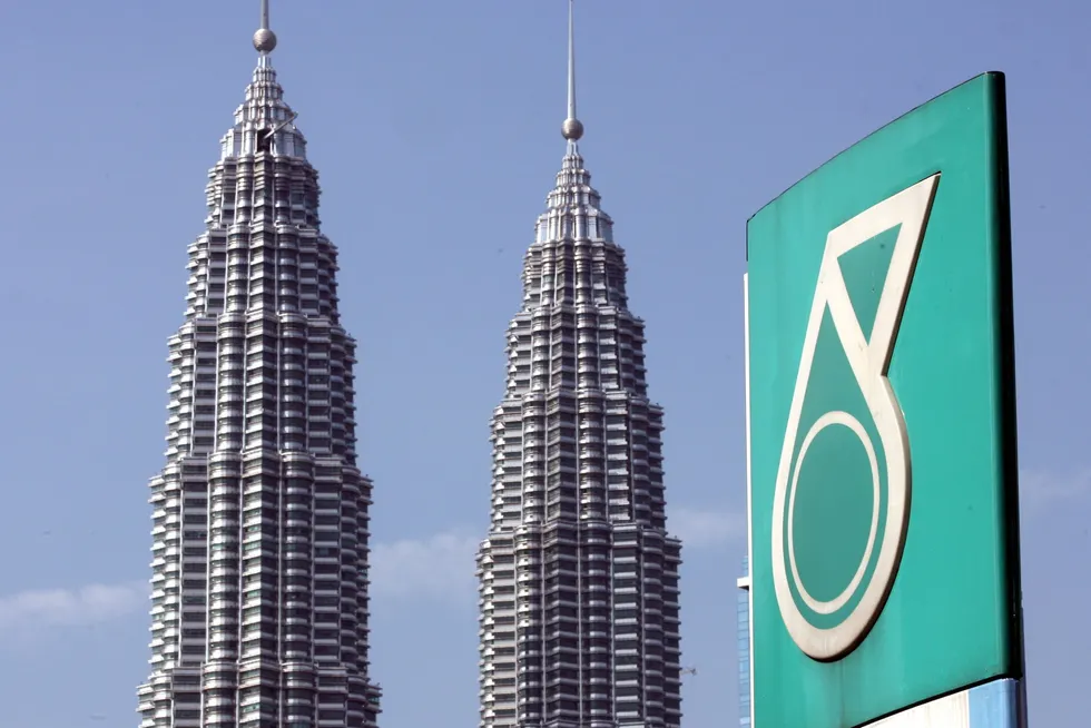 The Petronas twin towers is seen behind the company's corporate logo in downtown Kuala Lumpur