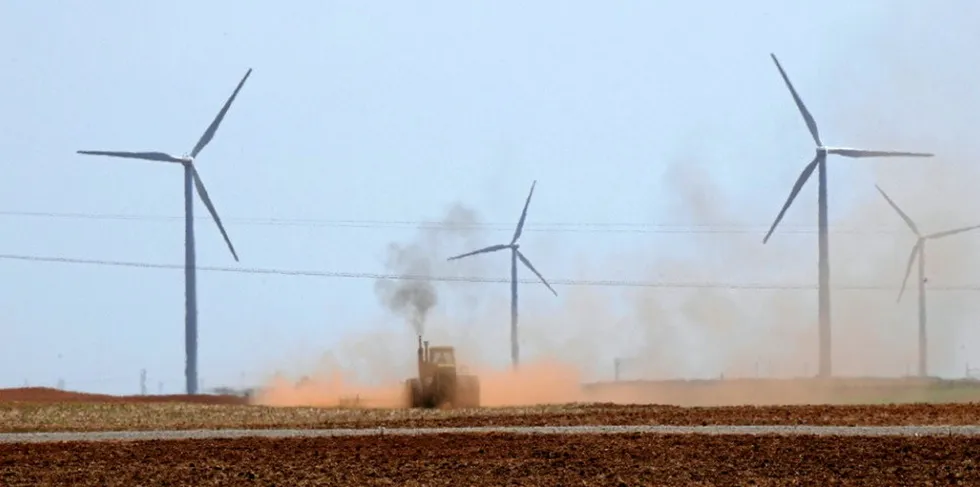 Tractor ploughs fields around wind farm in Oklahoma