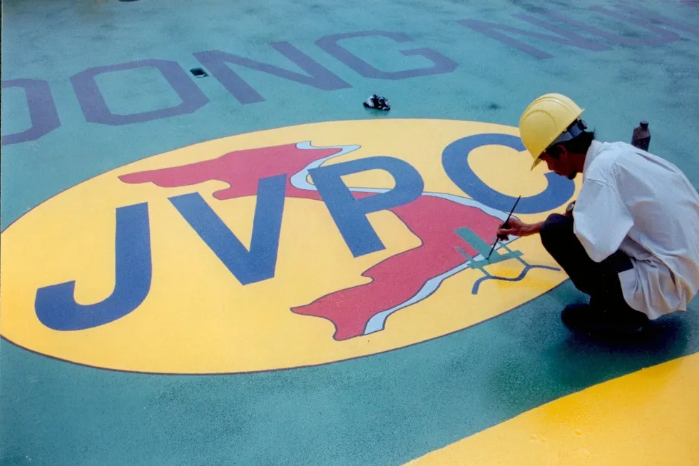 Worker painting the JVPC logo on a wellhead platform for the Rang Dong field.