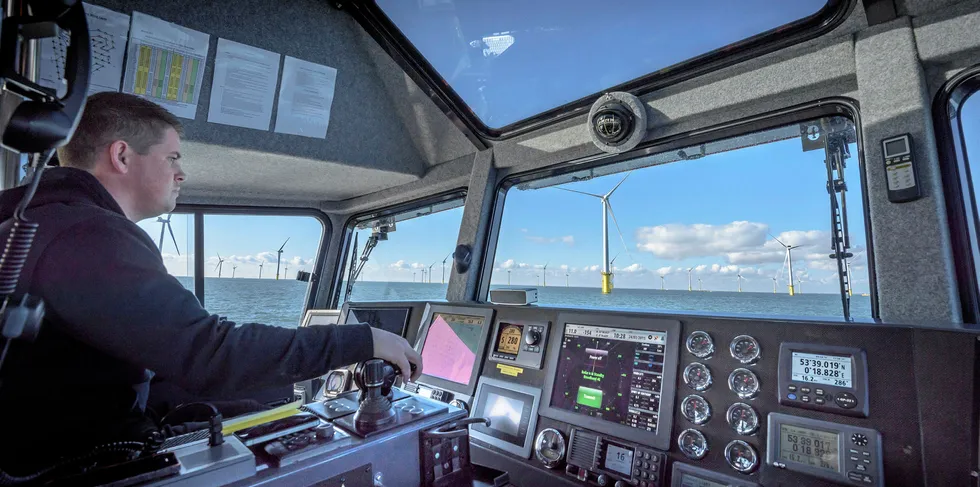 A fishing vessel travels past an offshore wind farm.