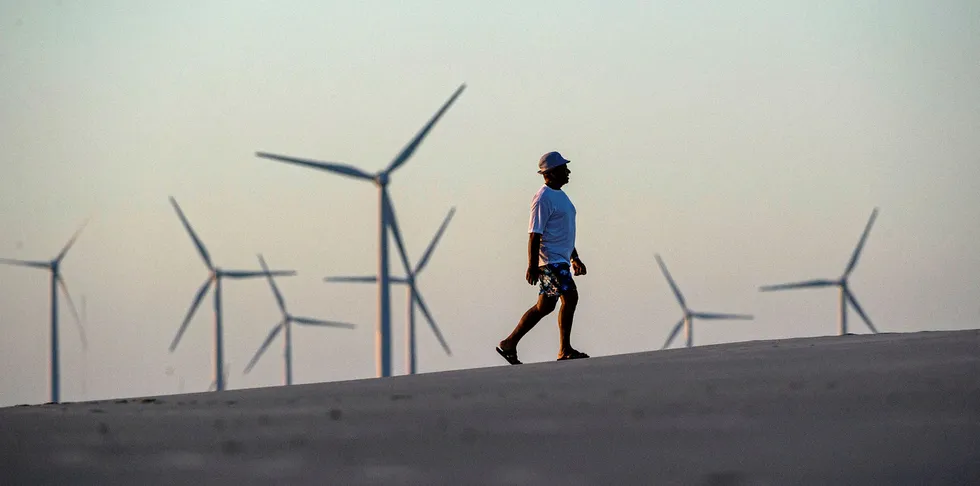 A man walk along the beach near wind turbines installed at Prainha do Canto Verde, near Aracati, some 120 km southeast of Fortareza, in the Brazilian state of Ceara.
