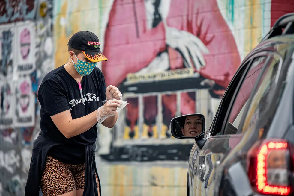 An employee of a pizza restaurant reads back an order to a customer after bringing her food, amid the global outbreak of the coronavirus disease, in Austin, Texas