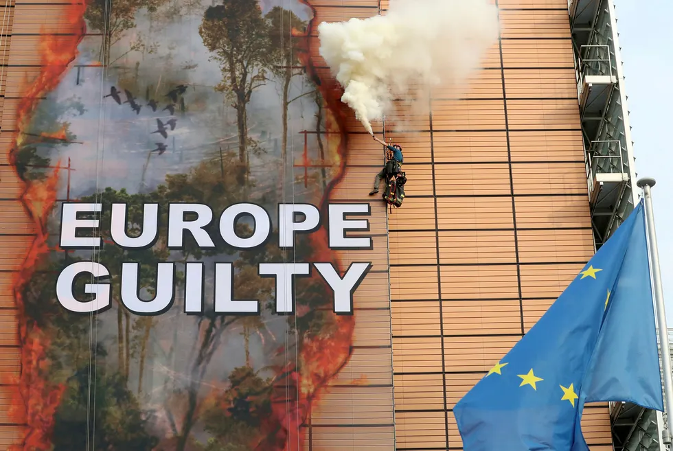 Climate protest: A Greenpeace activist releases smoke after rolling down a banner outside the European Union headquarters to protest against ongoing damage to the Amazon rain forest