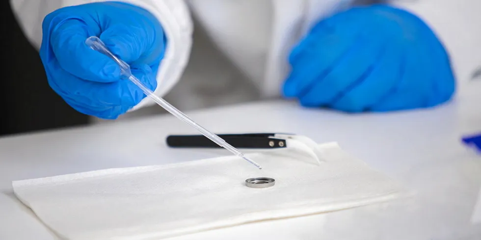 Lead researcher Tianyi Ma adds water as an electrolyte to a small battery.