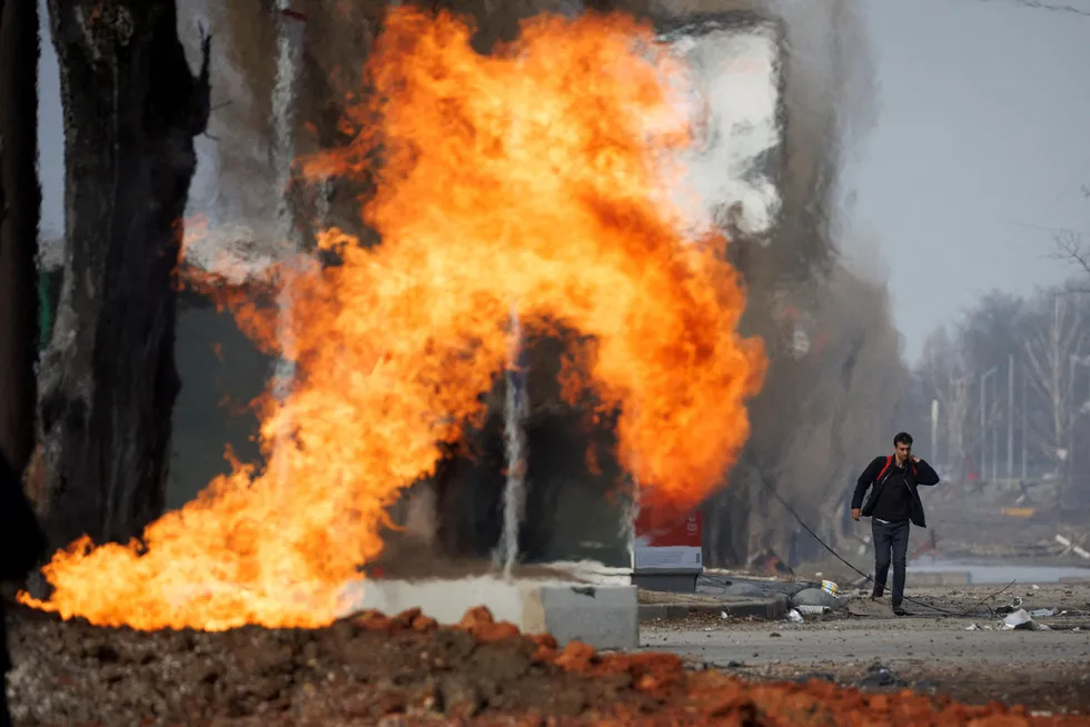 Toll rises: a man walks past a burning local gas pipeline that was hit during shelling from Russian positions in northern Kharkiv in March