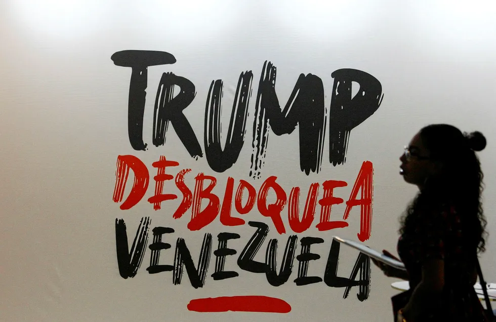 Ongoing crisis: a woman walks next to a sign that reads in Spanish "Trump, unblock Venezuela", a reference to US sanctions and measures aimed at toppling President Nicolas Maduro