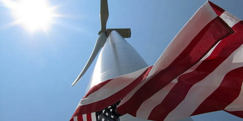 US flag flies below a wind turbine in the sun