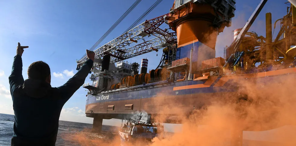 French sailor Clement Brochot gestures as he stands on the front deck of the fising boat "Galaxy III" in front of the drilling platform ship "Aeolus" in the Bay of Saint-Brieuc, western France.