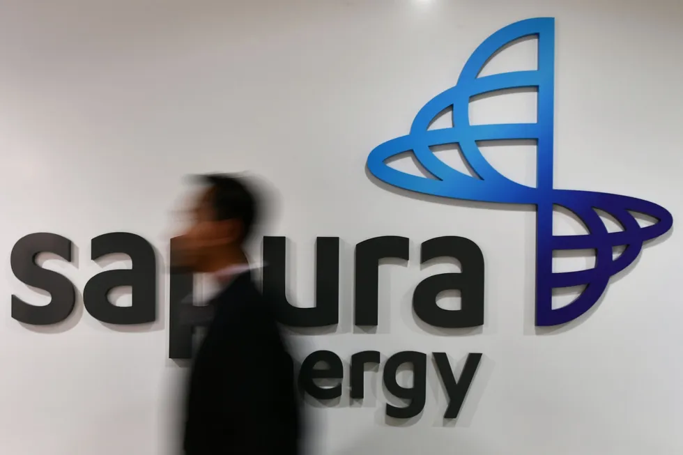 An employee walks past Sapura Energy’s logo at its headquarters in Kuala Lumpur, Malaysia.