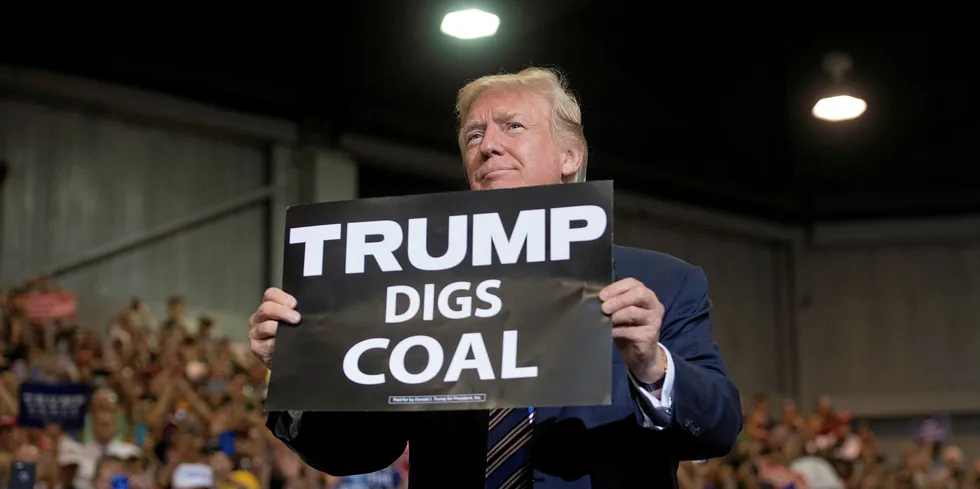 US President Donald Trump holds up a "Trump Digs Coal" sign as he arrives to speak during a Make America Great Again Rally.
