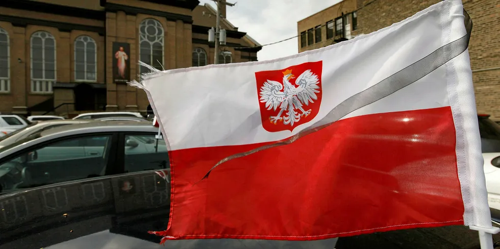 A Polish flag with a black streamer flies from a car.