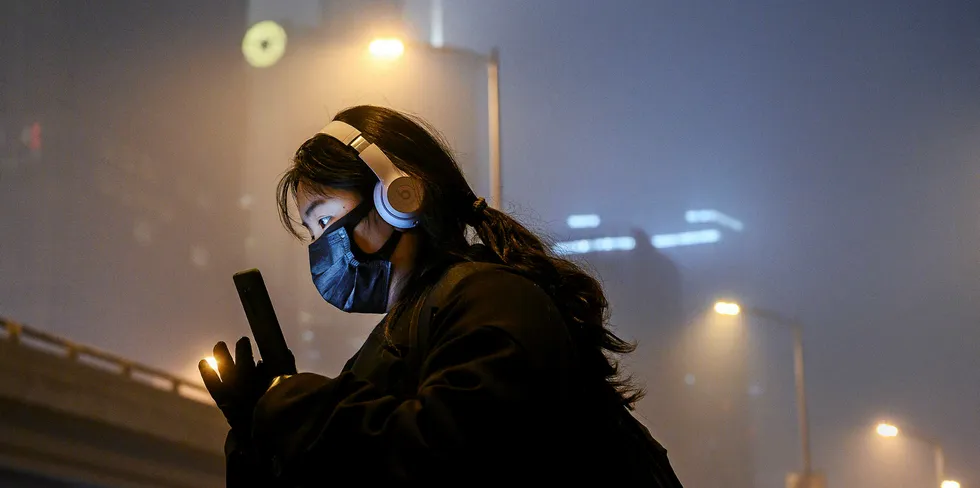 A Chinese woman wears a protective mask as she waits for a bus at a usually busy stop on February 13, 2020 in Beijing, China.