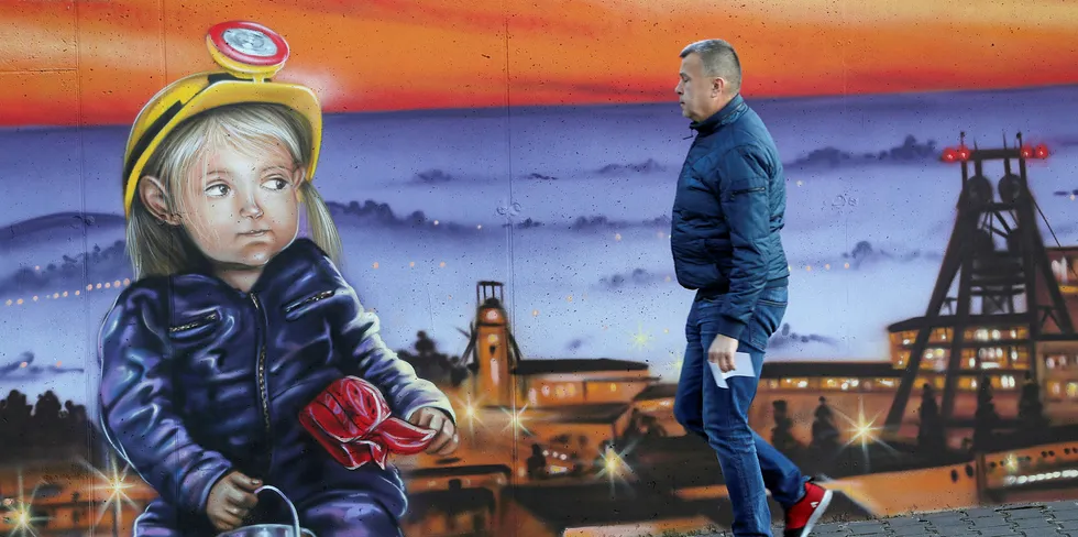 A man walks past a mural outside the corporate headquarters of the JSW mining company on November 30, 2018 in Jastrzebie Zdroj, Poland. JSW operates mines including the KWK Pniowek mine at nearby Pawlowice, Poland's largest coal mine.