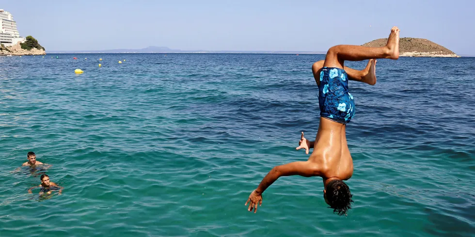 Boy jumps in the water on Magaluf Beach in Mallorca where tourism has suffered amid the Covid-19 pandemic