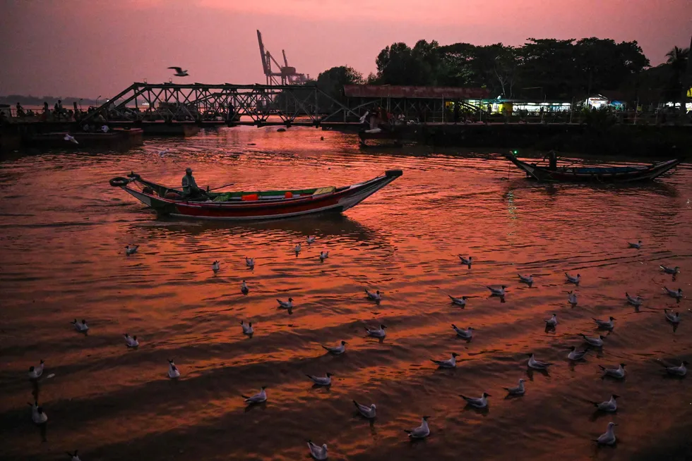 Scenic: a boatman steering his ferry at sunset along the Yangon River in Myanmar