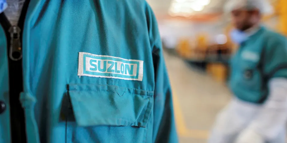 The Suzlon Energy Ltd. logo is displayed on an employee's uniform at the company's rotor blade manufacturing plant in Bhuj, India.