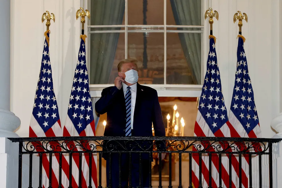 Out of hospital: US President Donald Trump reaches to remove his mask upon return to the White House from Walter Reed National Military Medical Center on 5 October