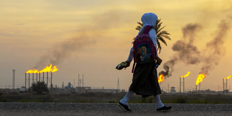 A girl carries her school bag as she walks in the Nahr Bin Omar village, across from the eponymous oil field and facility in Iraq's southern Basra governorate.