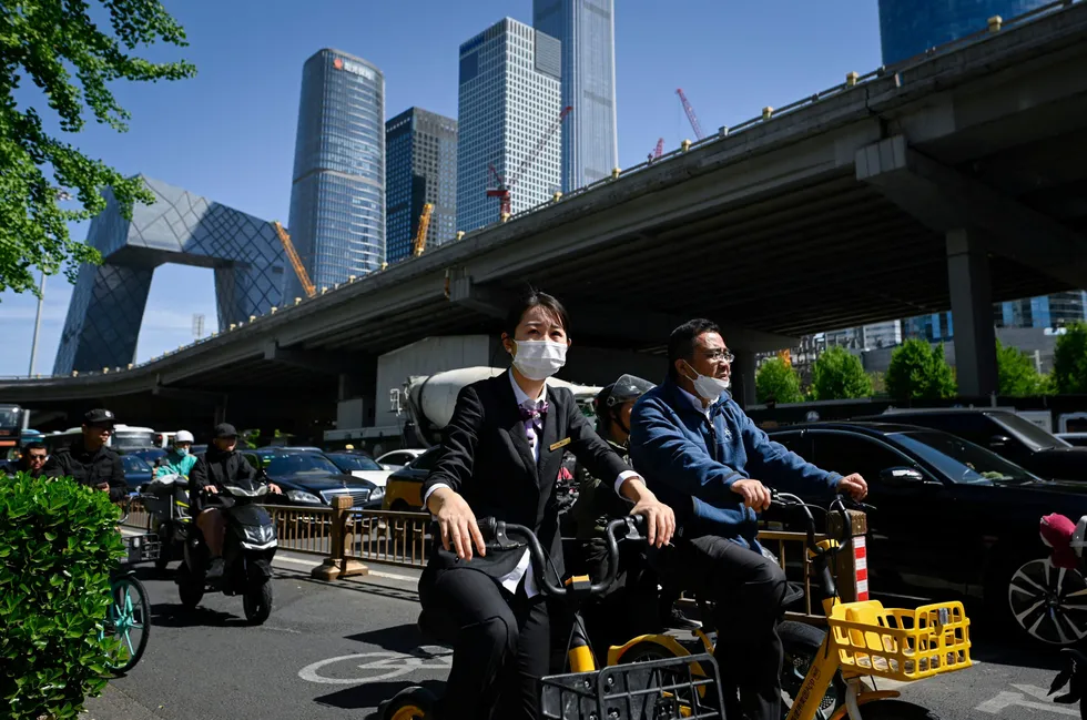 People ride bicycles along a street at a business district in Beijing.