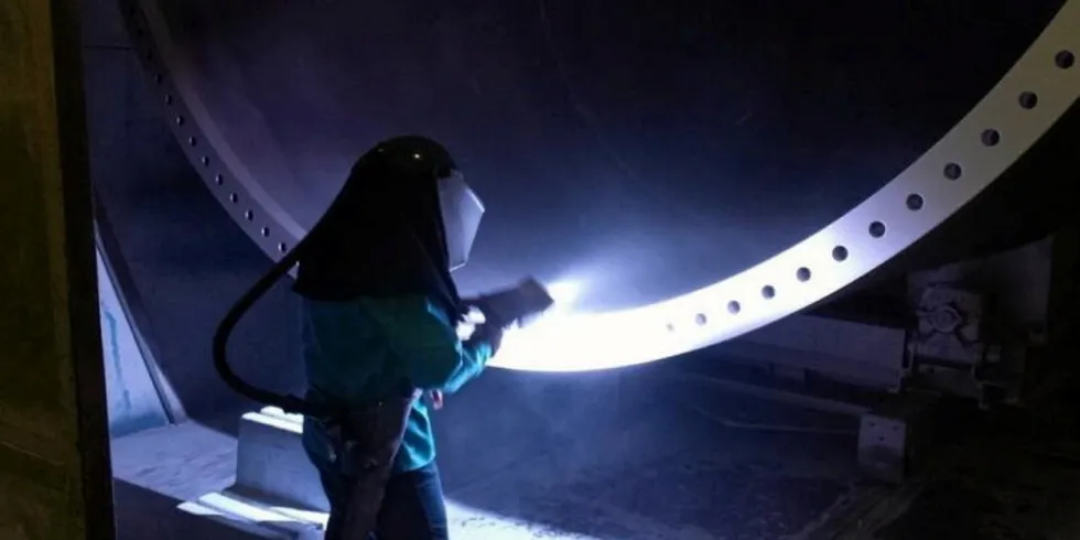 Arcosa worker applying coating protection for a wind tower section.