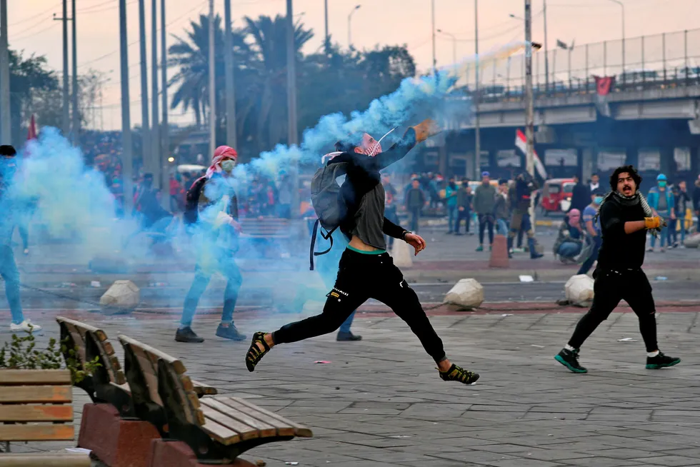 Street violence: an anti-government protester throws back a tear gas canister fired by riot police during clashes in Baghdad, Iraq