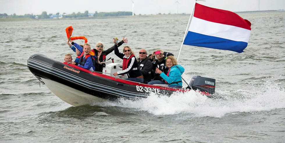 People in a boat watch the official visit of the Dutch King and Queen on the Ijsselmeer Lake