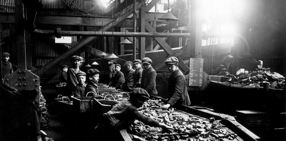 December 1910: Young boys at work at the troughs used for cleaning coal at a pit in Bargoed, South Wales. (Photo by Topical Press Agency/Getty Images) .