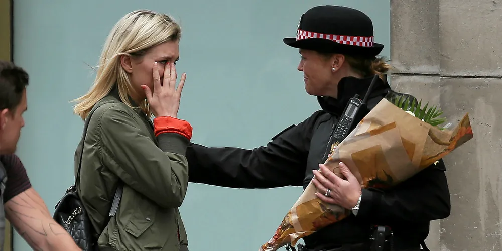 A police officer comforts a woman who has asked her to place flowers at the scene of Saturday's attack Photo: AFP/Getty