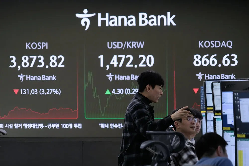 Currency traders work near a screen showing the Korea Composite Stock Price Index (KOSPI), left, and the foreign exchange rate between U.S. dollar and South Korean won, center, at the foreign exchange dealing room of the Hana Bank headquarters in Seoul, South Korea, Friday, Nov. 21, 2025. (AP Photo/Ahn Young-joon)