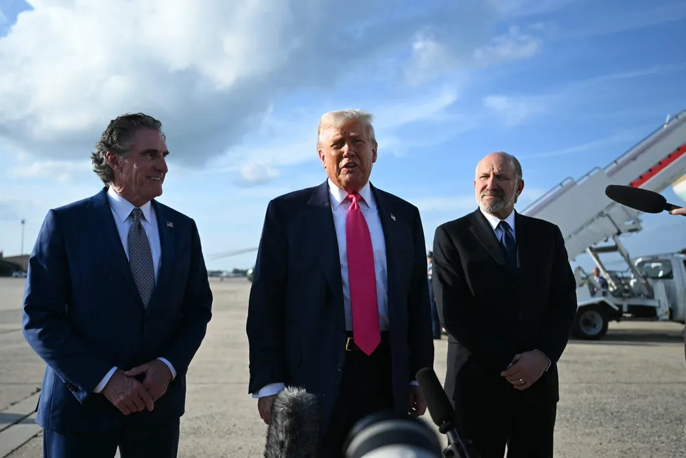 US President Donald Trump (centre), flanked by US Secretary of the Interior Doug Burgum (left) and US Secretary of Commerce Howard Lutnick (right), speaks to reporters after stepping off Air Force One upon arrival at Joint Base Andrews, Maryland on 15 July 2025.