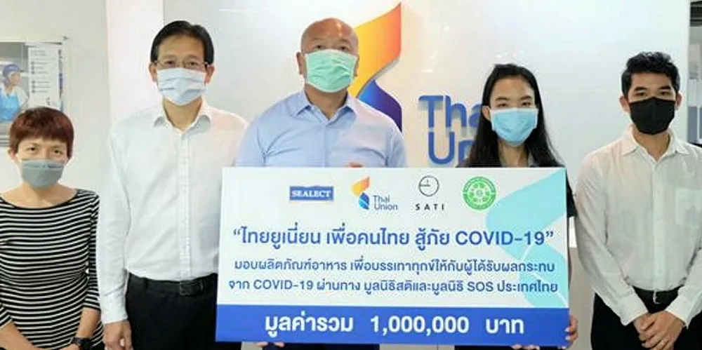 Thiraphong Chansiri, CEO of Thai Union Group, stands with colleagues as they present a donation of tuna to Thai communities impacted by coronavirus.