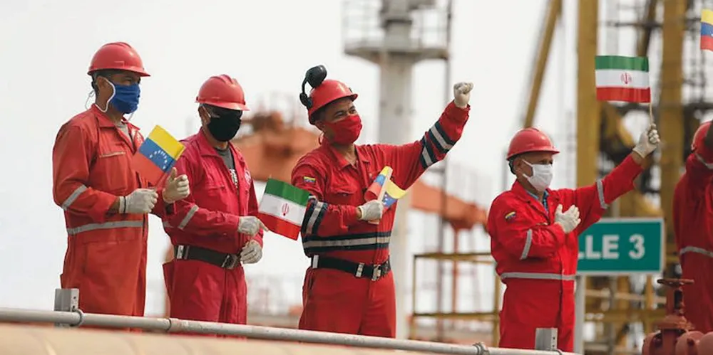 Workers of the state-oil company PDVSA holdi Iranian and Venezuelan flags as Iranian tanker Fortune arrives in June 2020