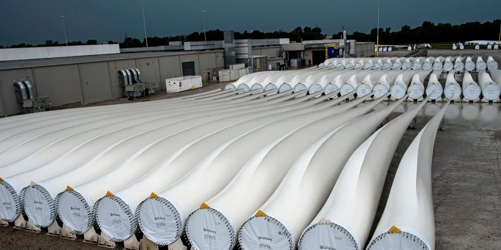 A worker walks past finished blades awaiting transport at the Siemens wind turbine blade plant in Fort Madison, Iowa
